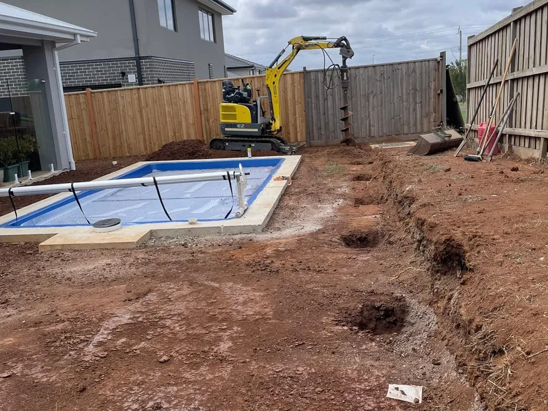 Sloping Taylors Hill backyard before earthworks, with uneven ground and weeds.