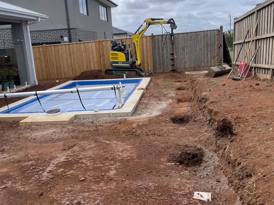 Sloping Taylors Hill backyard before earthworks, with uneven ground and weeds.